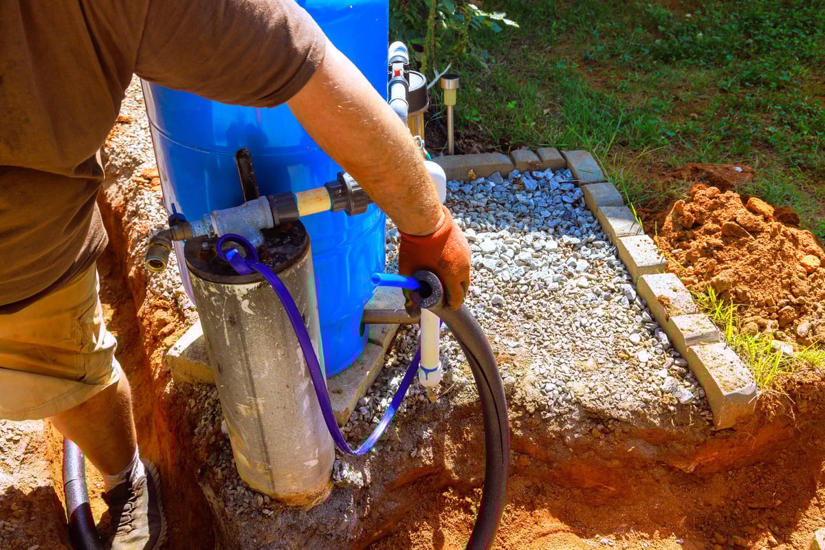 An plumber is connecting artesian water well pump in backyard