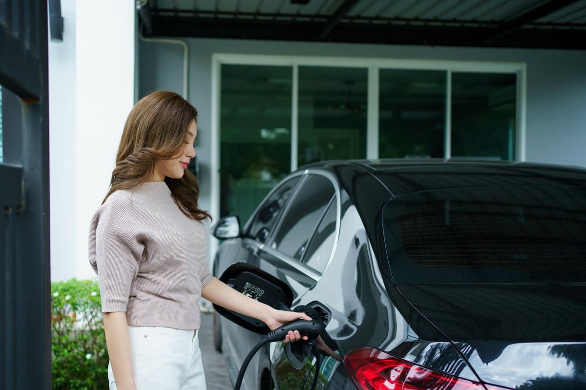 Woman charges her electric vehicle at home
