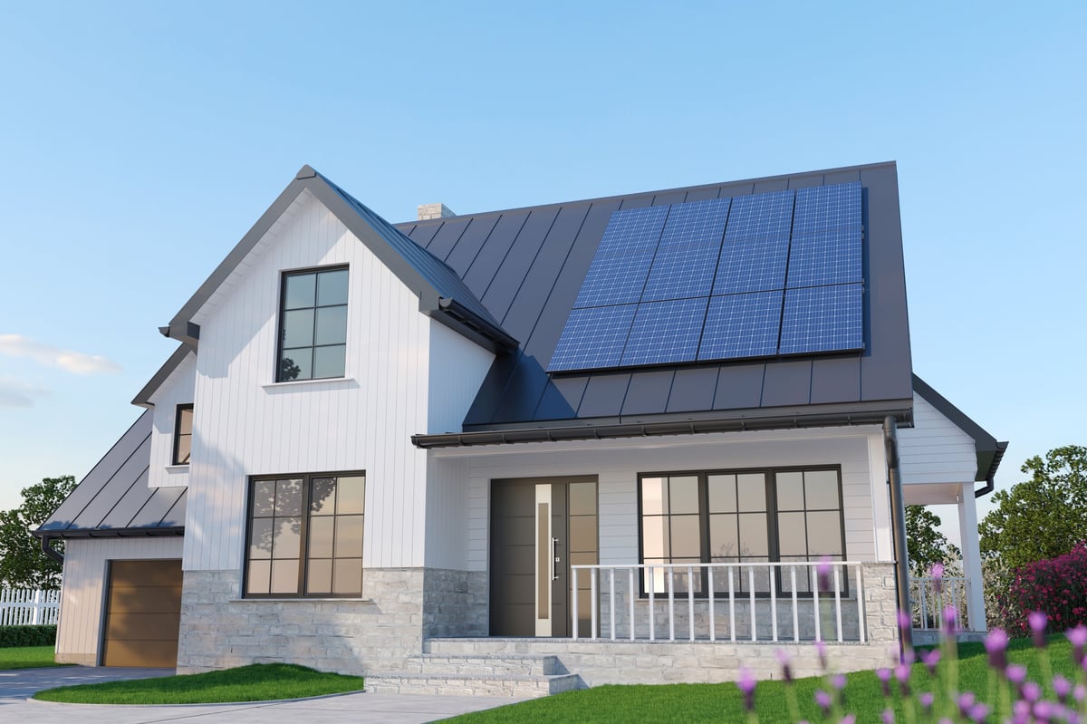 Modern single-family American house with rooftop solar panels installed on a dark metal roof. Sustainable suburban home architecture showcasing renewable energy, clean electricity generation and eco-friendly living concept.