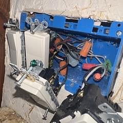 Disassembled electric motor or compressor with blue metal housing, internal wiring, and black components visible inside